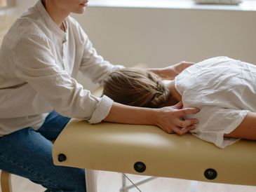 A person receiving a gentle head massage while lying on a massage table.
