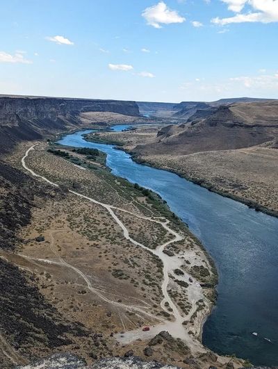 A winding river flowing through a rocky canyon under a blue sky.