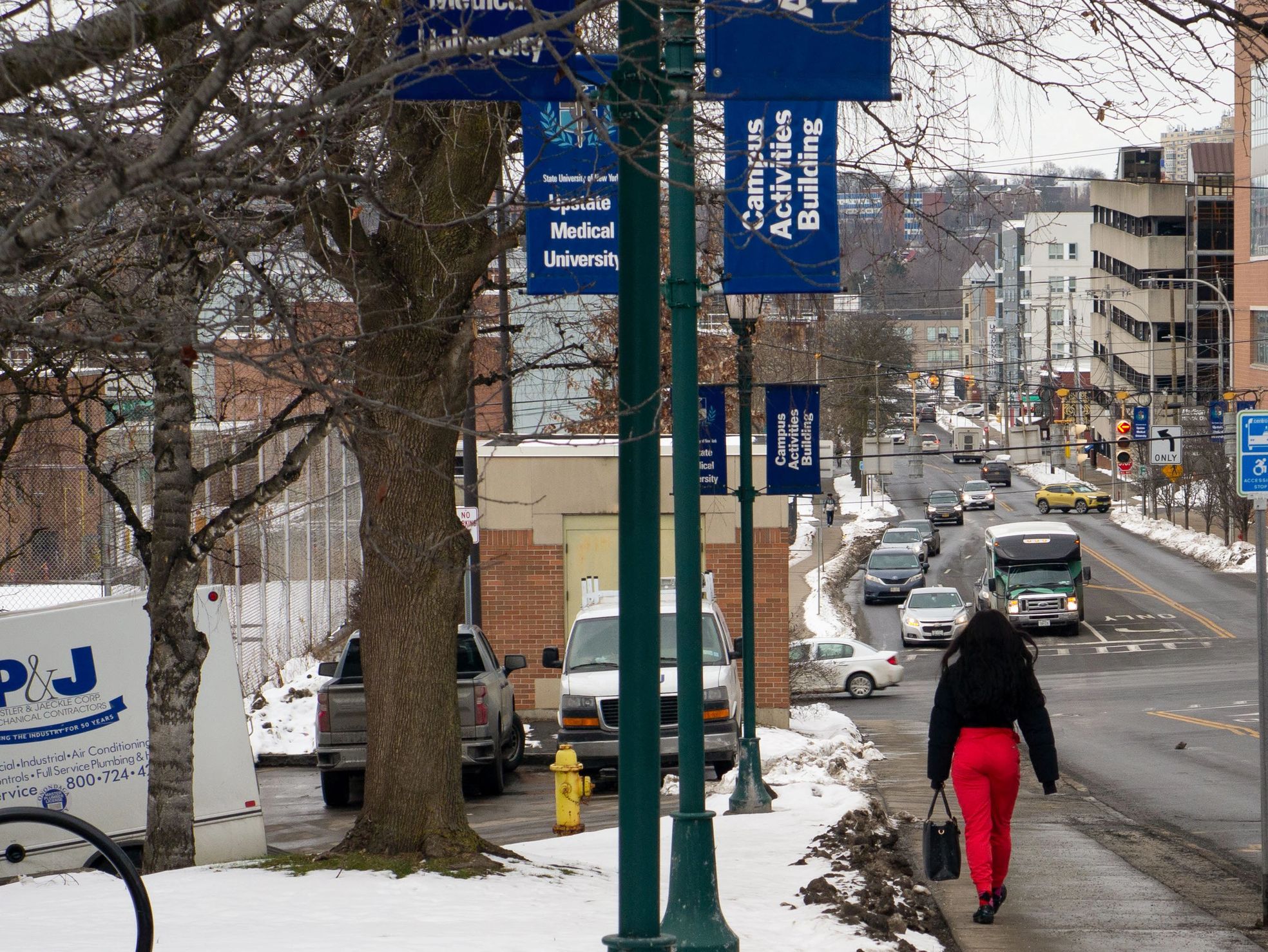 Woman in scrubs walks away from Upstate University Medical School campus