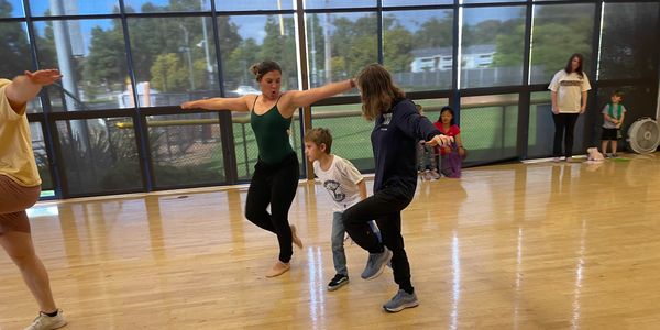 A group of children and adults dancing together in a dance studio