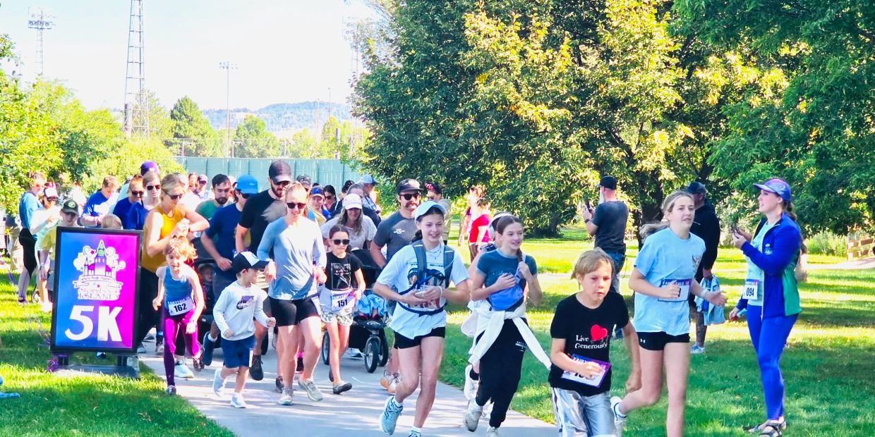 Group of people running a 5K race in a sunny park.