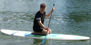 Young man kneeling on a paddle board