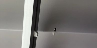 Close-up of a ceiling hook with a hanging clip near a beam.