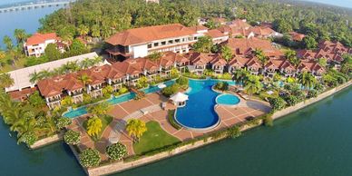 A luxurious waterfront resort with a large pool and lush greenery.