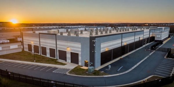 Modern industrial building at sunset with ample parking space.