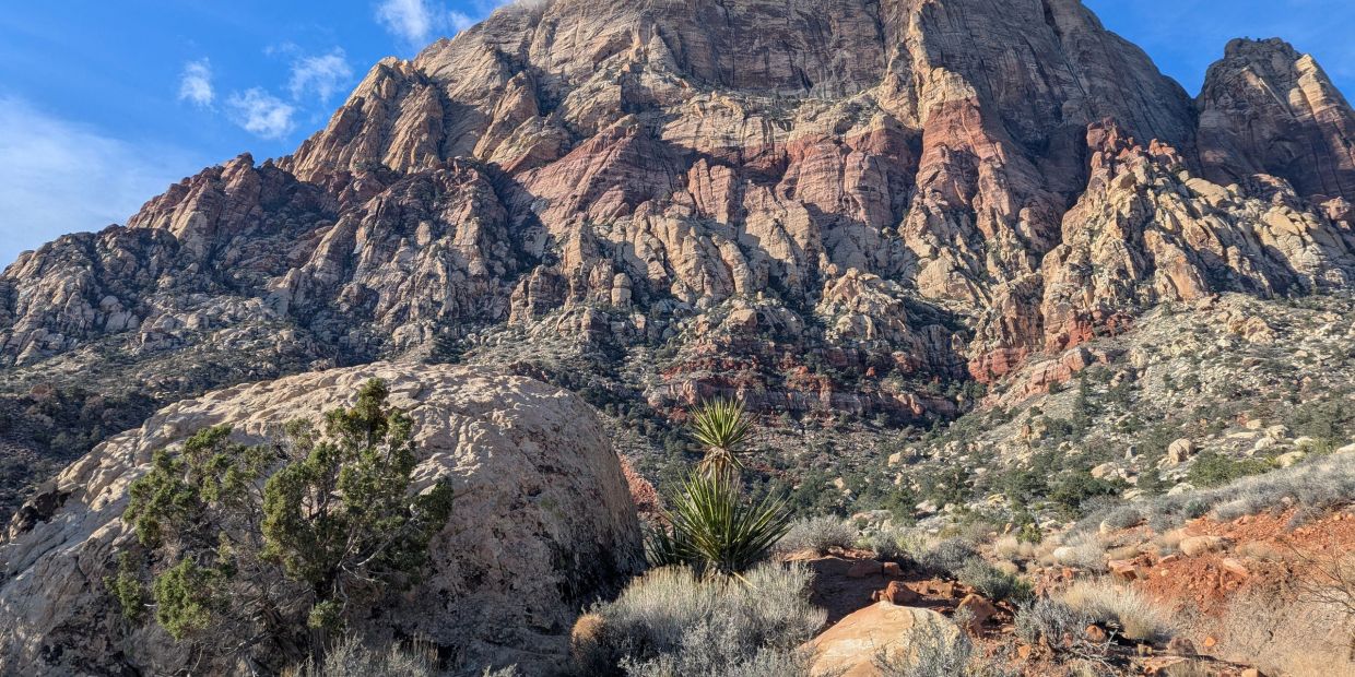 Rocky mountain landscape with sparse vegetation under a blue sky.