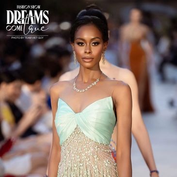 Model walking runway in elegant mint and gold dress at Dreams Come True fashion show.