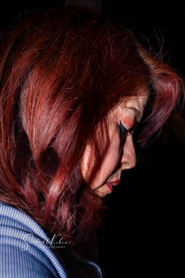 Close-up side profile of a woman with red hair against a black background.