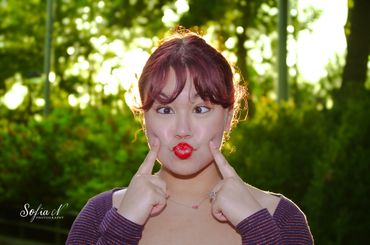 A woman making a playful face with crossed eyes and puckered lips outdoors.