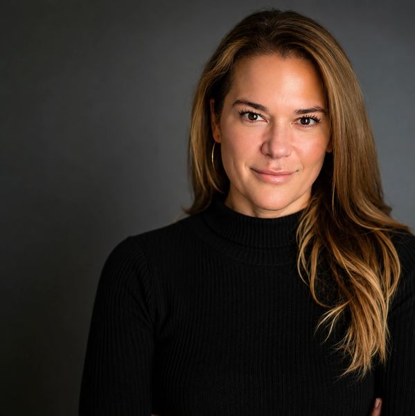 Confident woman with long hair wearing a black turtleneck sweater.