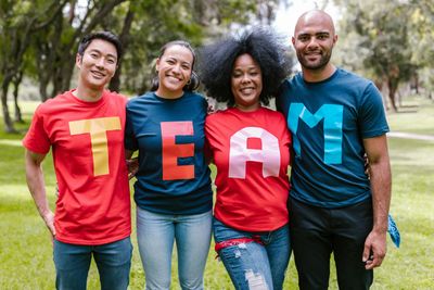 4 people standing wearing tshirts that spell out TEAM