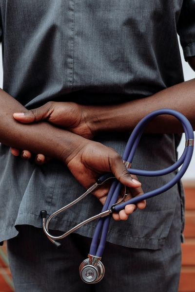 Hands behind back with a blue stethoscope in the left hand