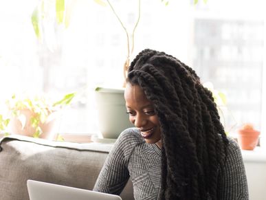 Black woman with Marley twists looking at a laptop screen