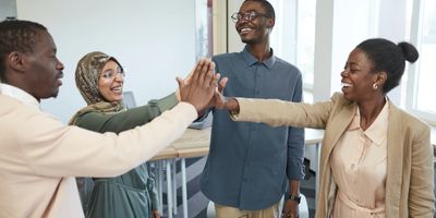 Four people smiling and high-fiving together