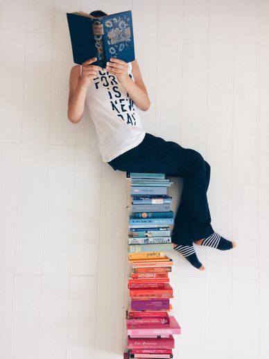 Sitting on a stack of colorful books while reading a book