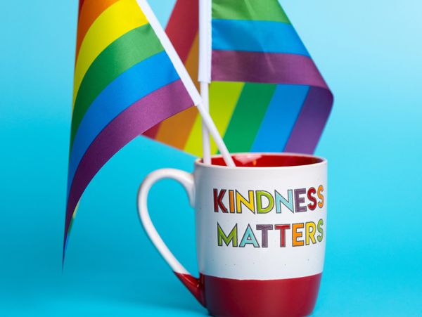 Mug with "Kindness Matters" inscribed. The mug contains two pride flags.