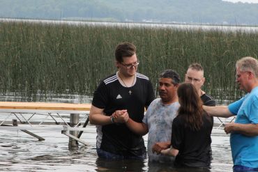A group of people standing in water during a baptism ceremony.
