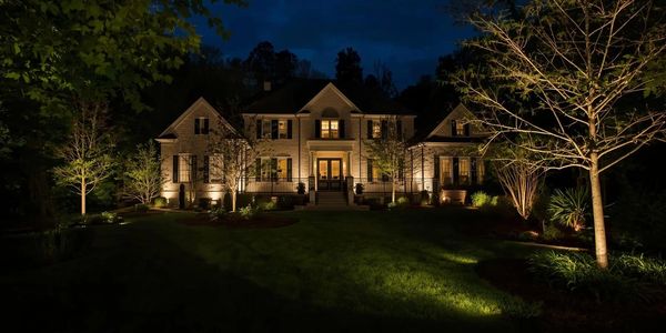 Elegant house lit beautifully at night with garden lights.