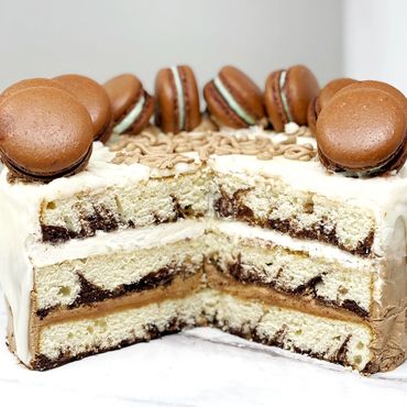 Marble cake showing interior. Chocolate, vanilla frostings. 10 chocolate macarons on top.