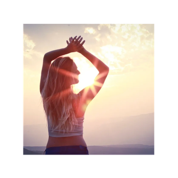 Woman enjoying sunrise with arms raised, silhouetted against the sun.