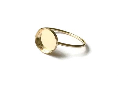 A simple gold ring with a round flat bezel on a white background.