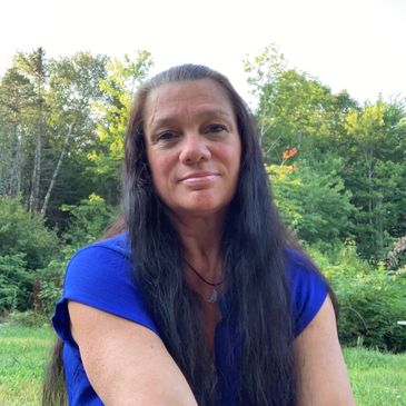 Woman with long dark hair wearing a blue shirt outdoors.