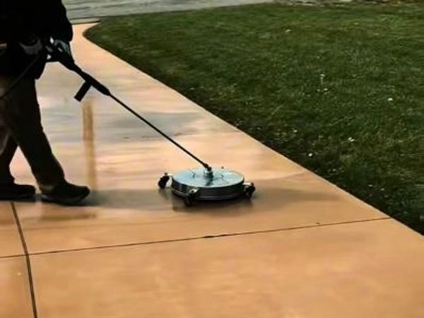 Person using a surface cleaner on a concrete sidewalk.
