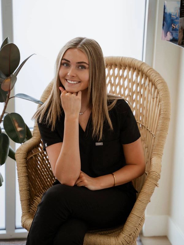 Smiling woman sitting on a wicker chair indoors.