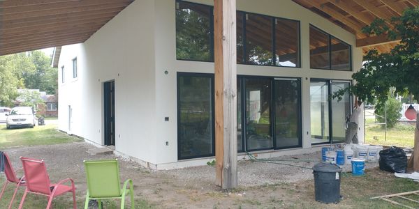 Modern house under construction with large windows and outdoor seating.