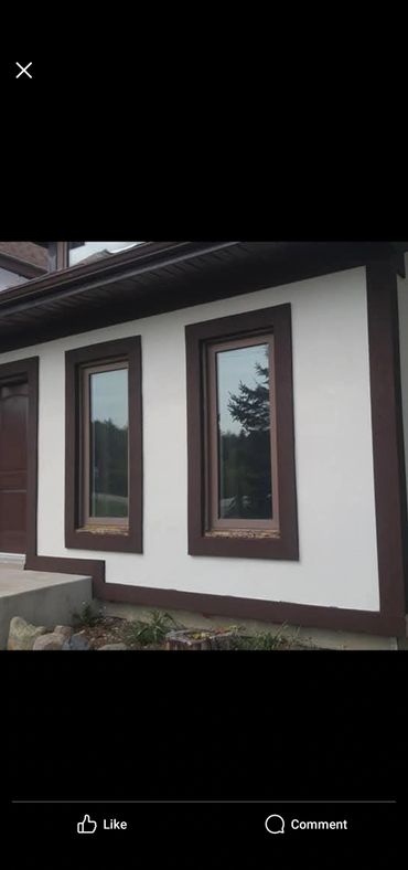 Two tall narrow windows on a white wall with brown trim.