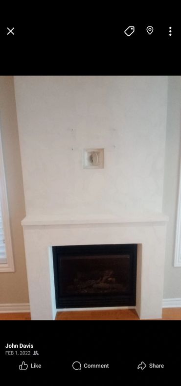Minimalist white fireplace with a black insert and a small vent above.
