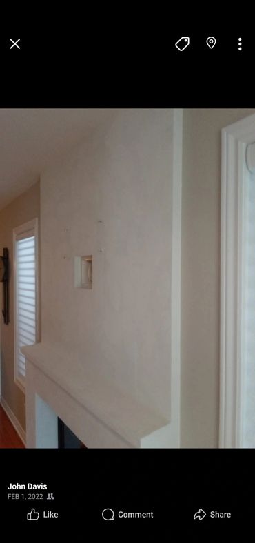 Plain beige fireplace wall with a small recessed niche and window blinds.