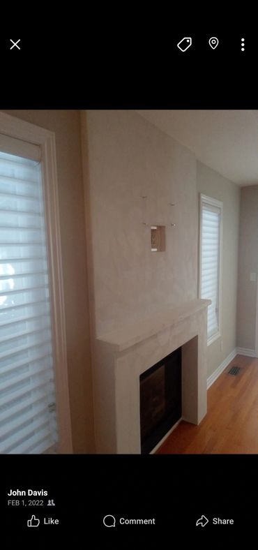 Minimalist fireplace with white walls and wood flooring in a bright room.