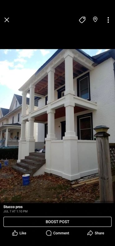 A white two-story porch with columns in front of a house under construction.