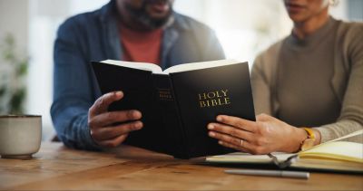 Two people reading the Holy Bible together.