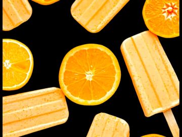 Orange popsicles and orange slices on black background.