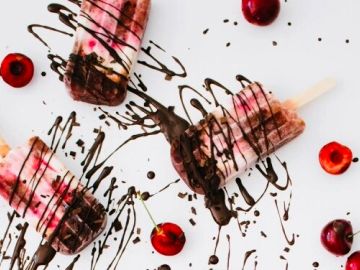 Cherry popsicles drizzled with chocolate on white.