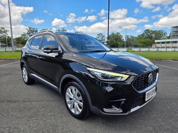 A sleek black MG SUV parked under a blue sky with clouds.