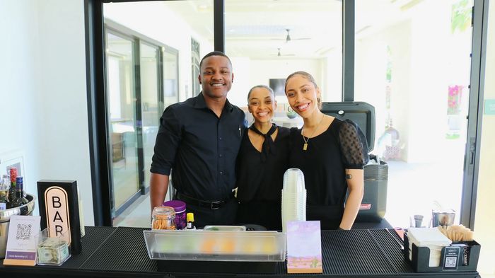 Three bartenders standing together smiling.