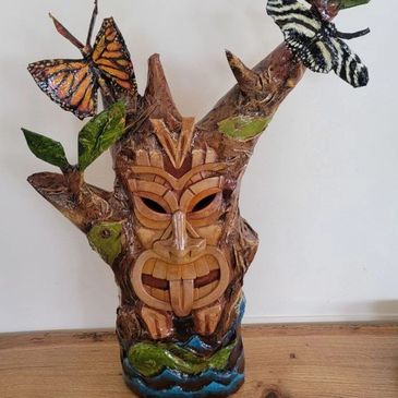 Wooden tiki carved with butterflies and leaves.