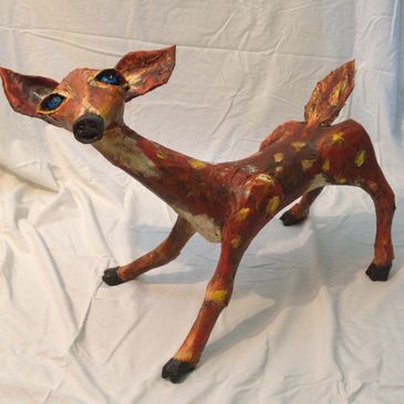 Paper mache deer sculpture with large blue eyes.