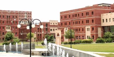 Modern red-brick buildings with fountains and green lawns.