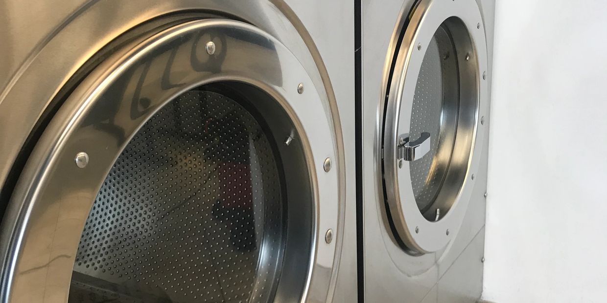 Two stainless steel front-loading washing machines in a laundry room.