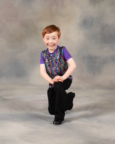 Smiling boy posing in colorful sequined vest.