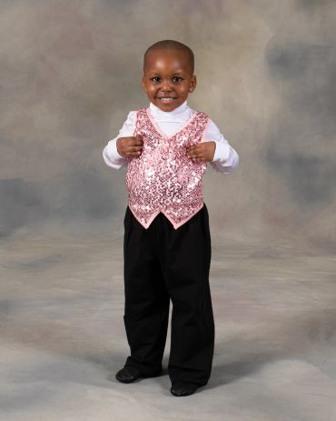 Smiling child in a pink sequined vest and black pants.