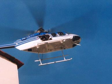 Hélicoptère blanc et bleu en vol contre un ciel bleu.