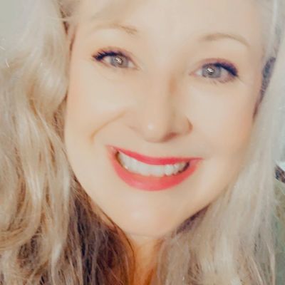 Close-up of a smiling woman with blonde hair and bright red lipstick.