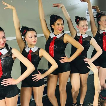 Young dancers in black and red costumes striking a pose.