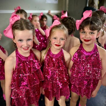 Three young girls in sparkly pink dance costumes.