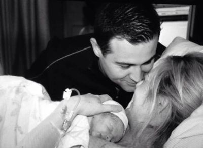New parents lovingly gaze at their newborn baby in a hospital room.